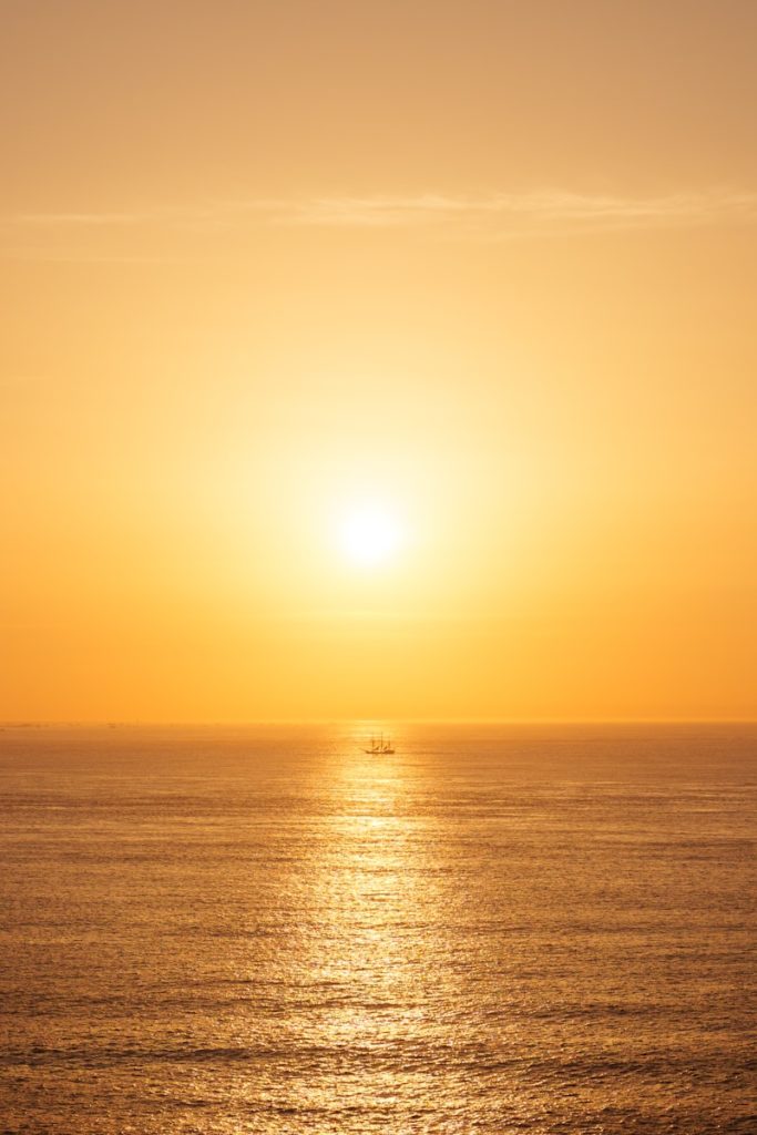 A small boat on the ocean at sunset.